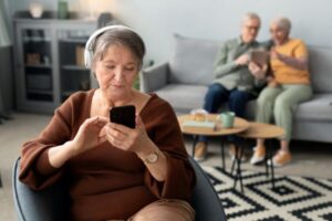 mulher senior ouvindo musica sentada na sala de estar emcasa. Rotina mais leve.