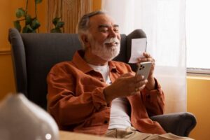 vista-lateral-idoso-segurando-smartphone