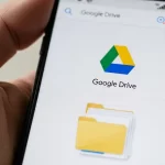 mão segurando um celular mostrando o logo do google drive